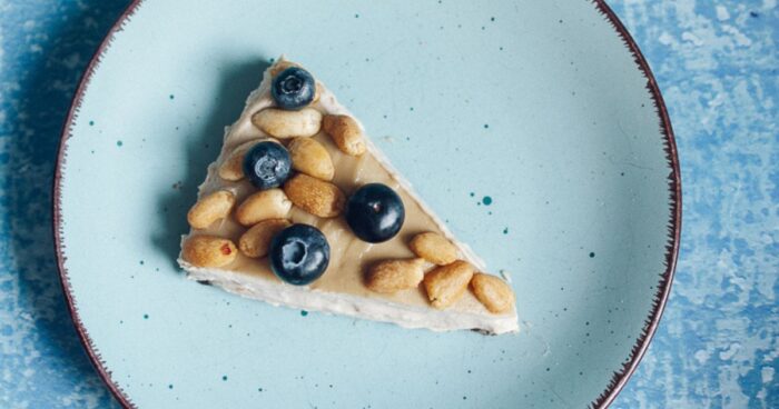 Hotový nepečený cheesecake ozdobte ovocím a arašidmi.